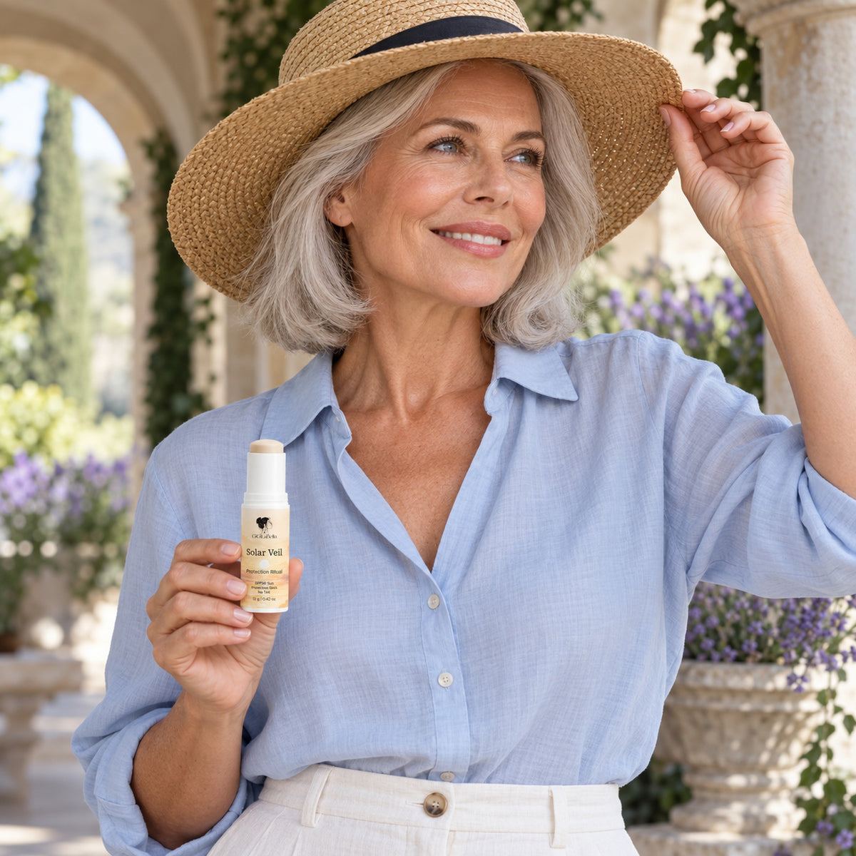 Mature woman in pale blue holds Solar Veil while adjusting a straw hat in a shaded garden loggia